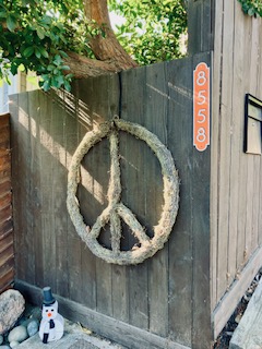 Großes Peace-Zeichen aus getrocknetem Moos an einer verwitterten Holzwand im Eingang eines Hauses im Laurel Canyon in Los Angeles