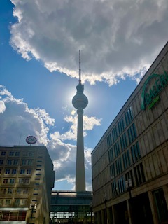 Fernsehturm Berlin im Gegenlicht mit Sonne und Wolken, hohe Gebäude auf dem Alexanderplatz