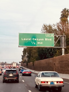 Verkehrsschild für Laurel Canyon Blvd, Ausfahrt 14, mit der Entfernung von 1/2 Meile, auf einer mehrspurigen Straße, im Vordergrund ein Oldtimer und moderne Autos