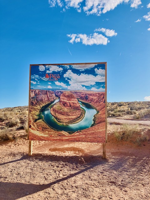 Altmodisches, gemaltes Informationsschild zeigt Horseshoe Bend, einen Flussbogen im Grand Canyon, mit blauem Himmel und Wolken