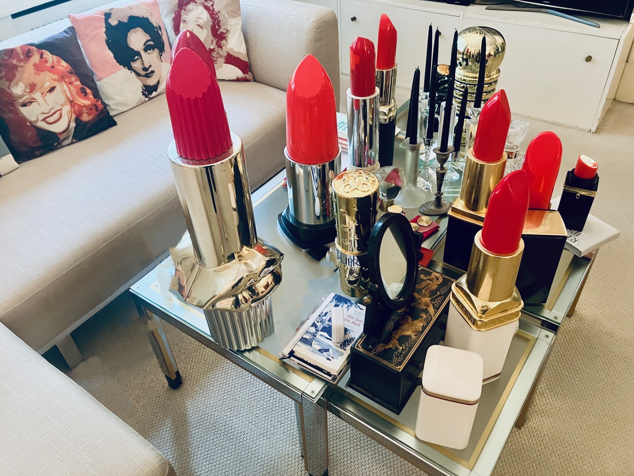 Verschiedene große Lippenstift-Skulpturen in Rot- und Pinktönen auf einem Couchtisch im Lippenstiftmuseum Berlin
