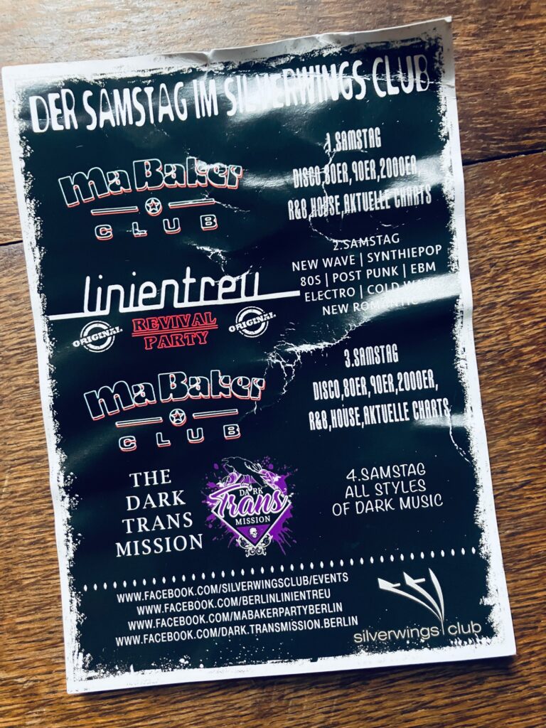 Schwarzer, leicht zerknitterter Werbezettel für Tanzveranstaltungen mit der Aufschrift: Der Samstag im Silverwings Club: Linientreu, 2. Samstag, New Wave, Synthiepop