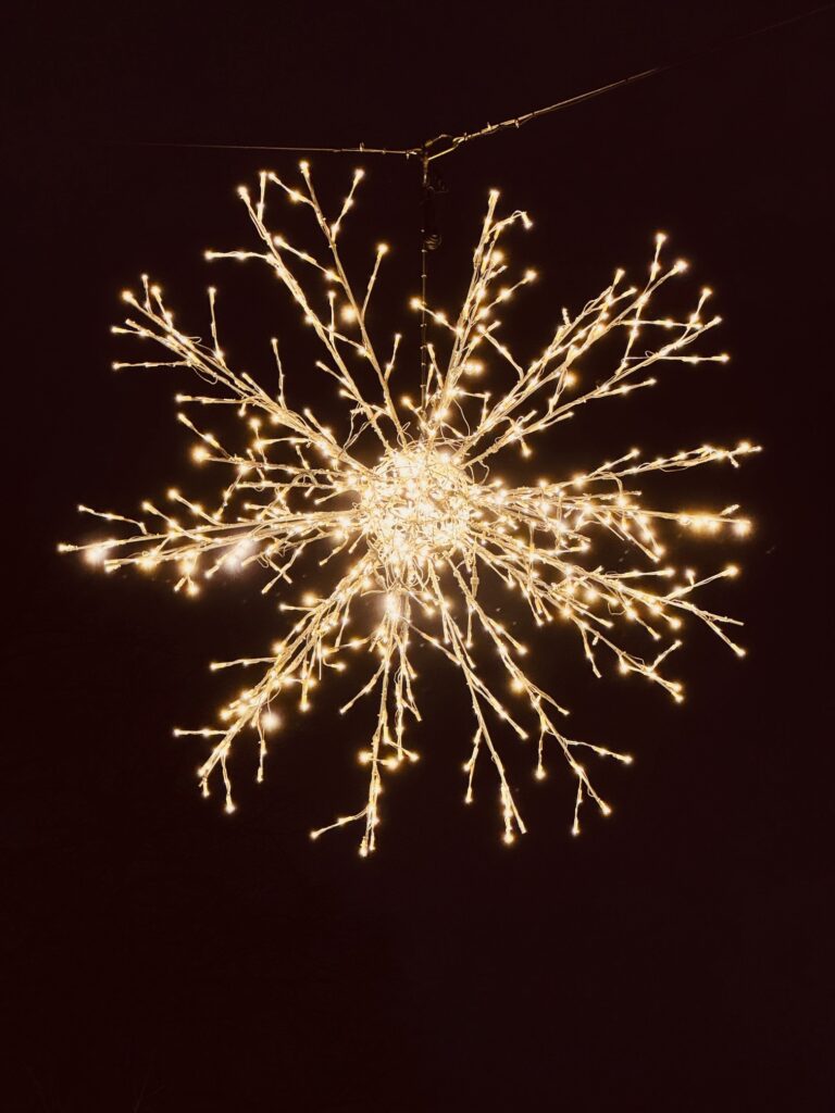 Leuchtender Weihnachtsstern aus vielen kleinen Lichterkettenzweigen vor dunklem Hintergrund