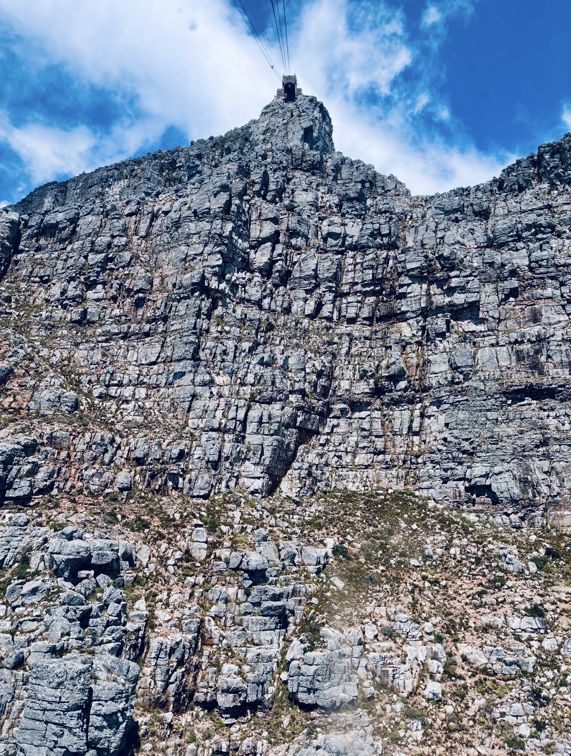 Nahaufnahme des Tafelbergs in Kapstadt mit steiler, zerklüfteter Oberfläche unter blauem Himmel mit Wolken