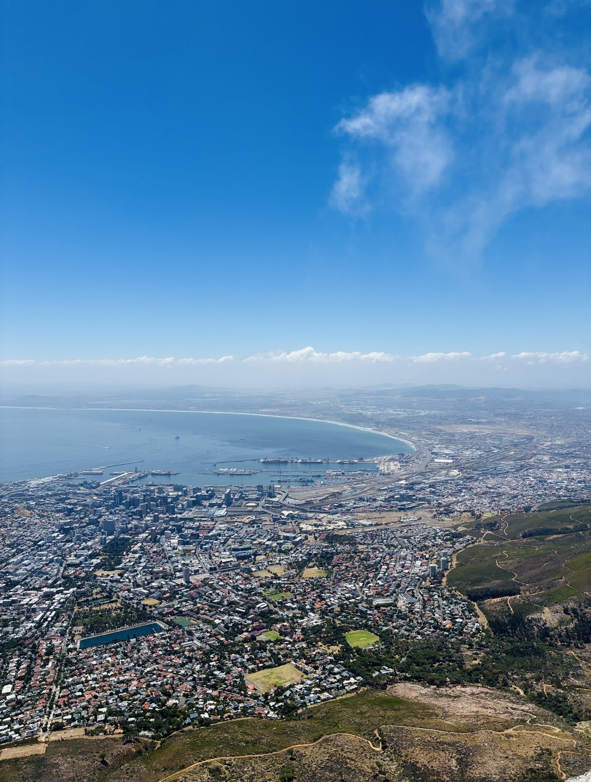 Blick vom Tafelberg auf Kapstadt mit dicht bebauten Stadtgebieten und Bergen im Hintergrund
