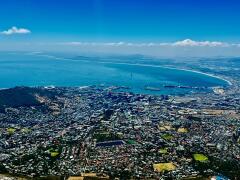Blick vom Tafelberg auf Kapstadt mit dicht bebauten Stadtgebieten und Bergen im Hintergrund
