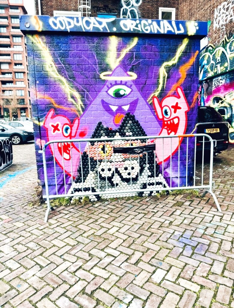 Mauer mit einem farbenfrohen Street Art-Gemälde, im Hintergrund Gebäude und geparkte Autos