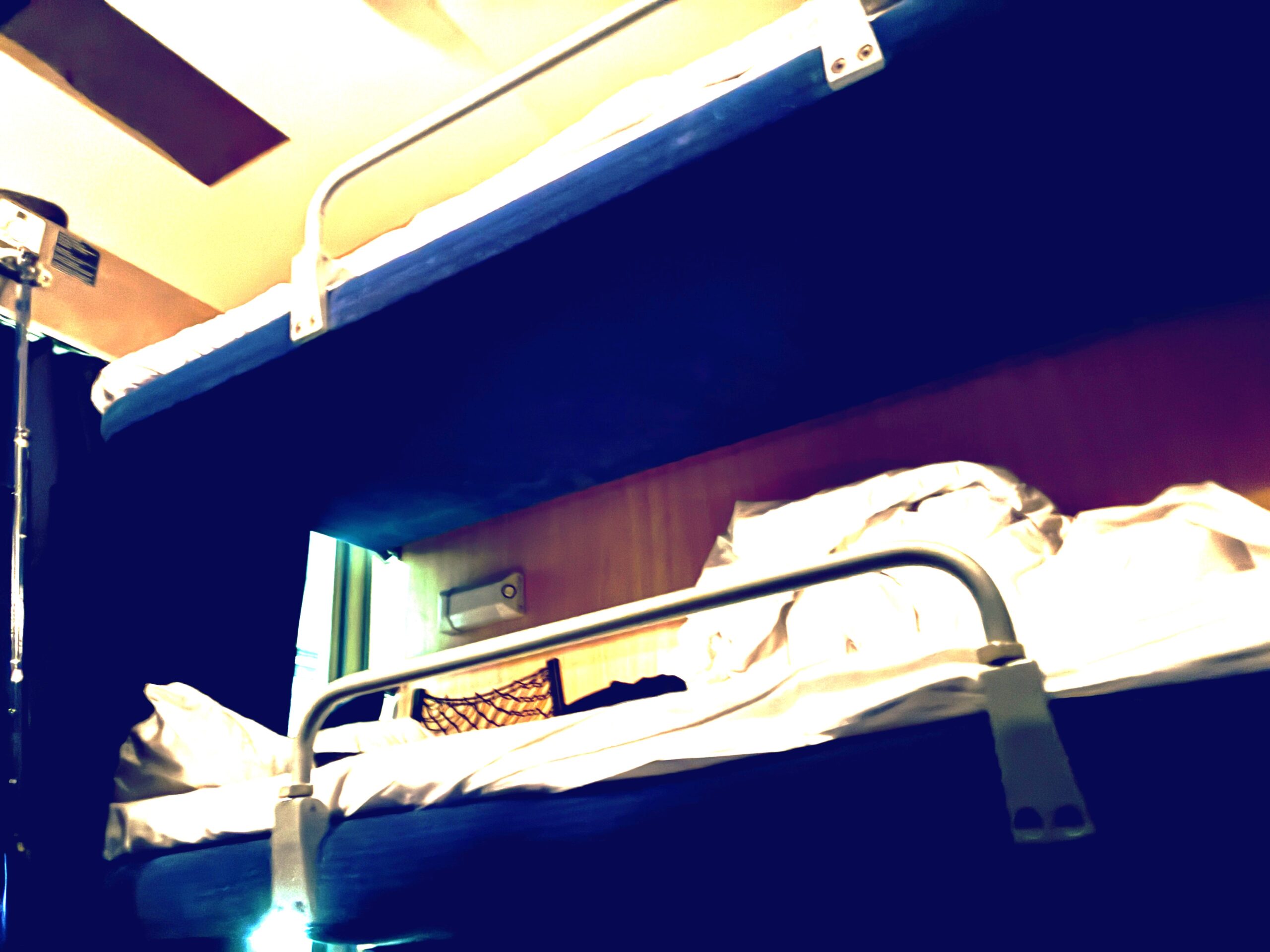 Zwei mit weißer Bettwäsche bezogene Liegen in einem altmodischen Liegewagen in einem Zug