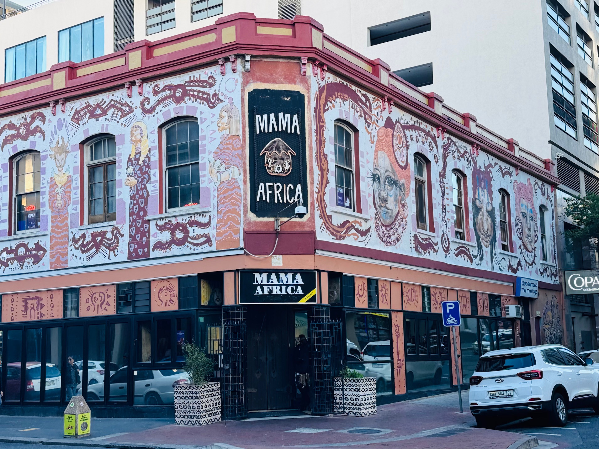 Eckgebäude mit Wandmalereien und Schriftzug 'MAMA AFRICA' über dem Eingang und an der Ecke
