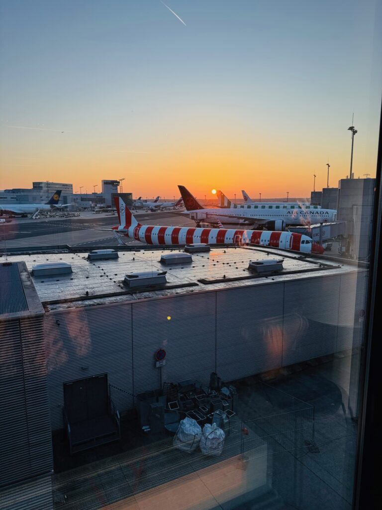 Flugzeuge auf dem Rollfeld des Flughafens Frankfurt am Main bei Sonnenaufgang mit orangefarbenem Himmel