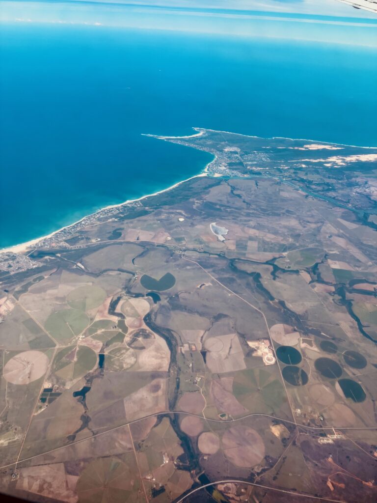 Luftaufnahme einer Küstenlandschaft mit landwirtschaftlichen Feldern und kreisförmigen Bewässerungsflächen