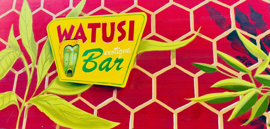 Schild im Tiki-Stil mit der Aufschrift 'WATUSI exotique Bar' vor rotem sechseckigem Muster und grünen Blättern