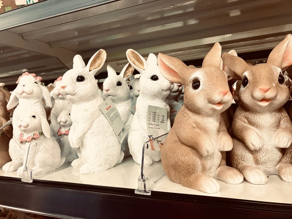 Gruppe von weißen und braunen Hasenfiguren aus Kunststoff auf einem Kaufhausregal