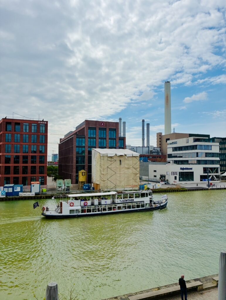 Hafen von Münster, auf dem Wasser ein Ausflugsboot mit dem Namen "MS Günther" und mehreren modernen Gebäuden im Hintergrund