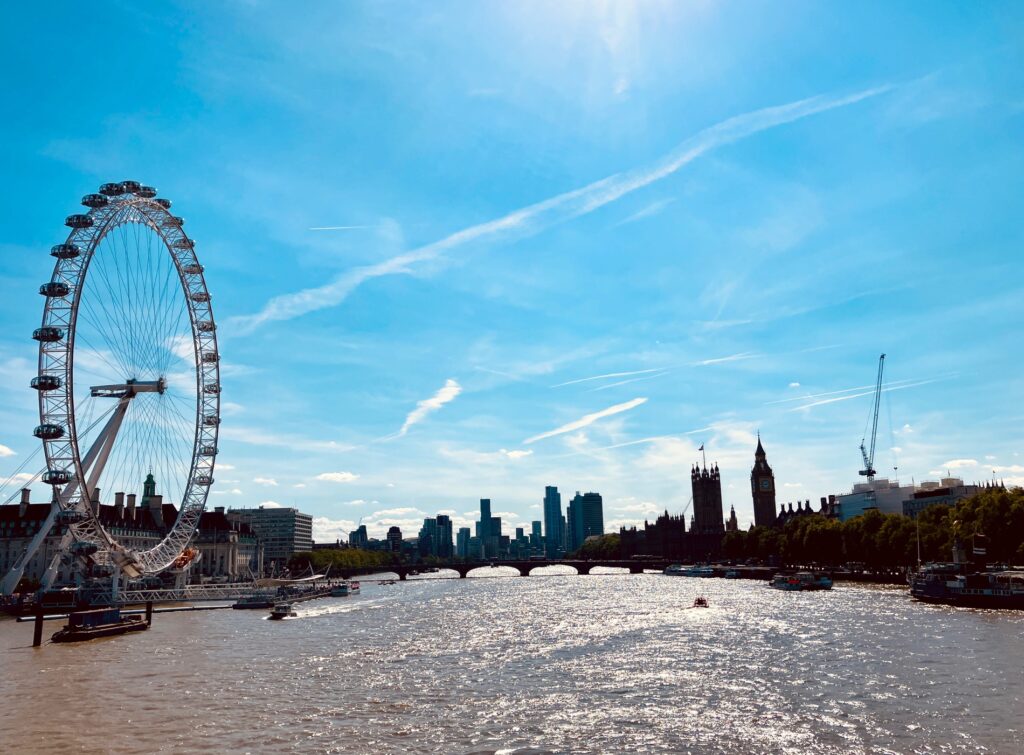 Blick auf die Themse mit dem London Eye links, mehreren Booten auf dem Wasser und der Silhouette von London mit dem Big Ben im Hintergrund