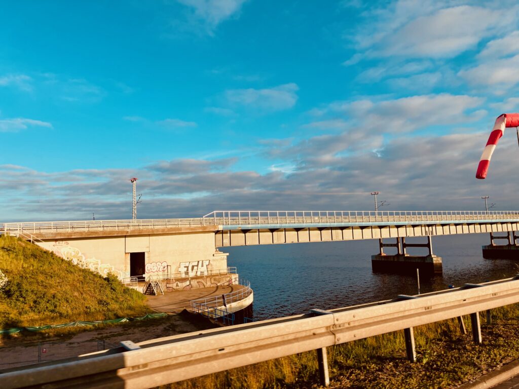 Brücke über Wasser mit Geländer und Graffiti an der Brückenunterseite bei bewölktem Himmel