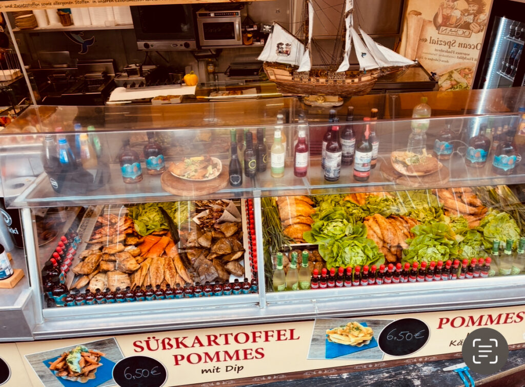 Theke mit Süßkartoffelpommes, verschiedenen Dips, Getränken und einem Modellsegelboot im Hintergrund