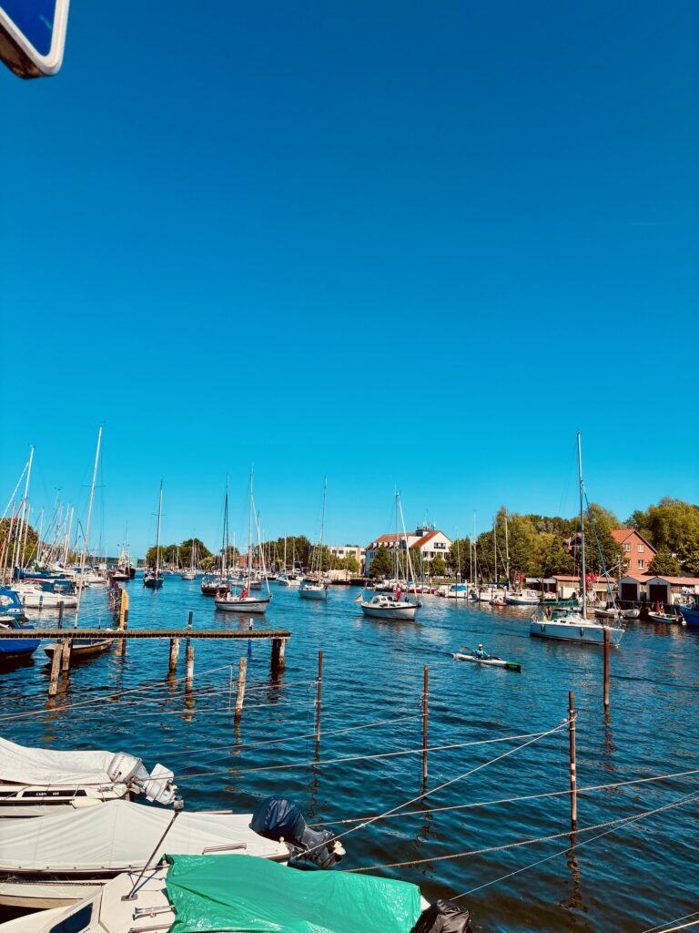 Fluss mit mehreren Segel- und Motorbooten auf blauem Wasser unter klarem Himmel