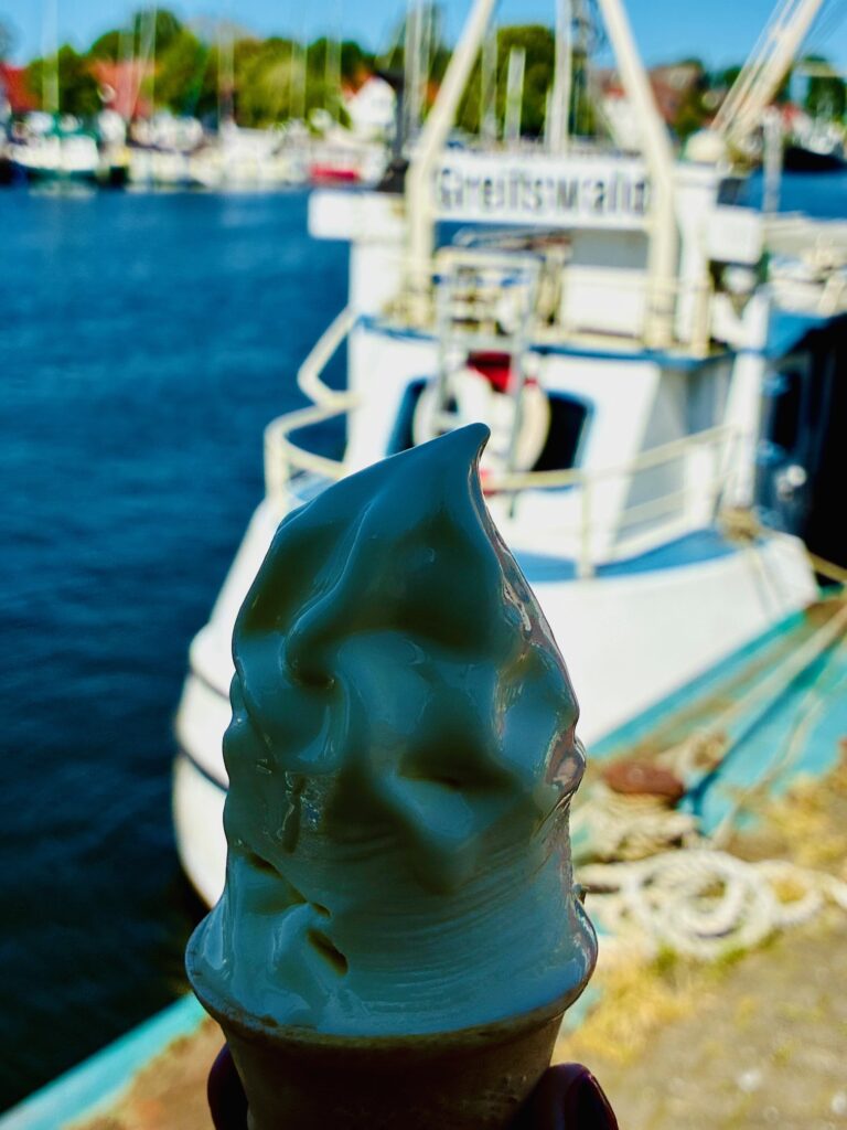 Softeis in einer Waffel vor einem Hafen mit Booten