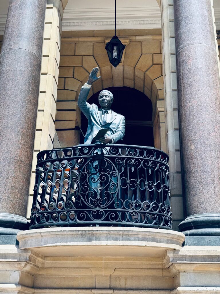 Verzierte Balkonbrüstung mit lebensgroßer Bronzestatue von Nelson Mandela in lebensechter Pose