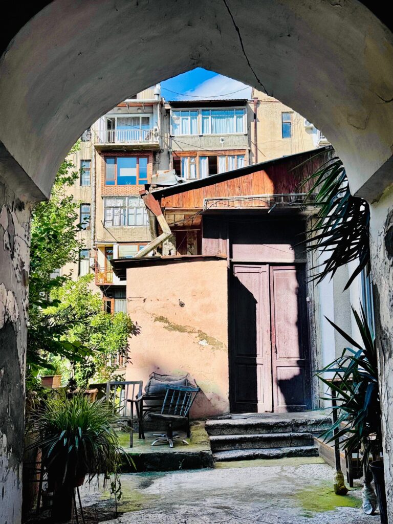 Blick durch Torbogen, dahinter verschachtelte Gebäude unter blauem Himmel