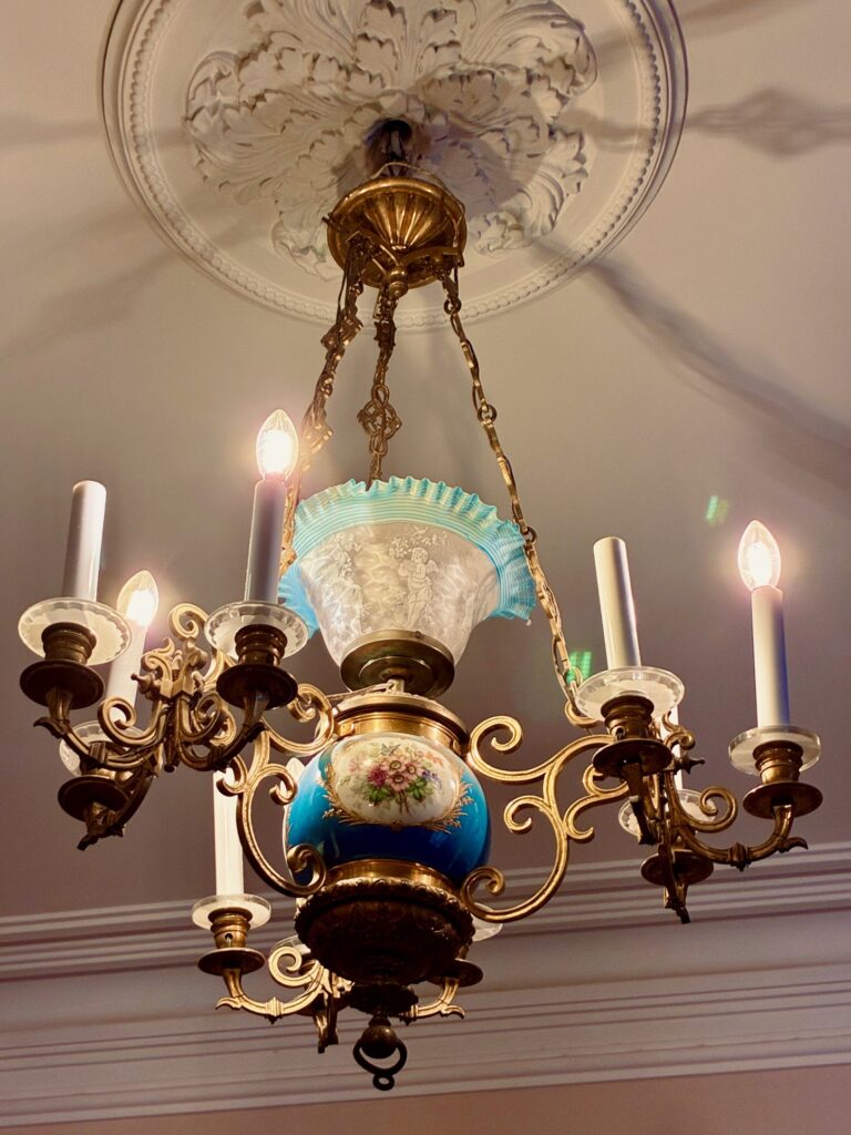 Antike Kronleuchter mit fünf Kerzenlampen und verziertem Porzellanelement mit Blumenmotiv an der Decke