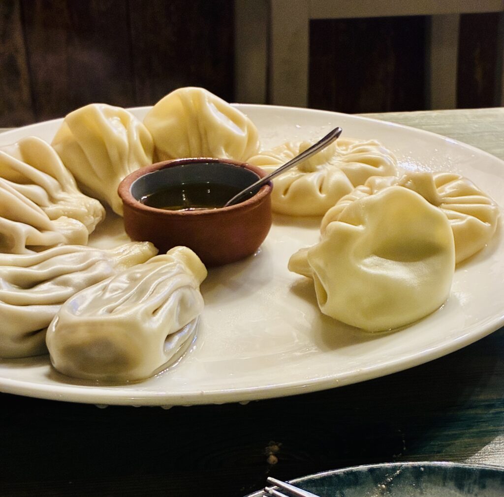 Teller mit georgischen Teigtaschen Khinkali und in der Mitte einer kleinen Schale mit Öl und einem Löffel