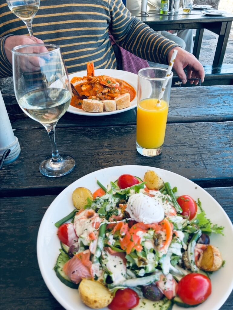 Teller mit buntem Salat, daneben ein Glas mit Orangensaft und ein Glas mit Weißwein