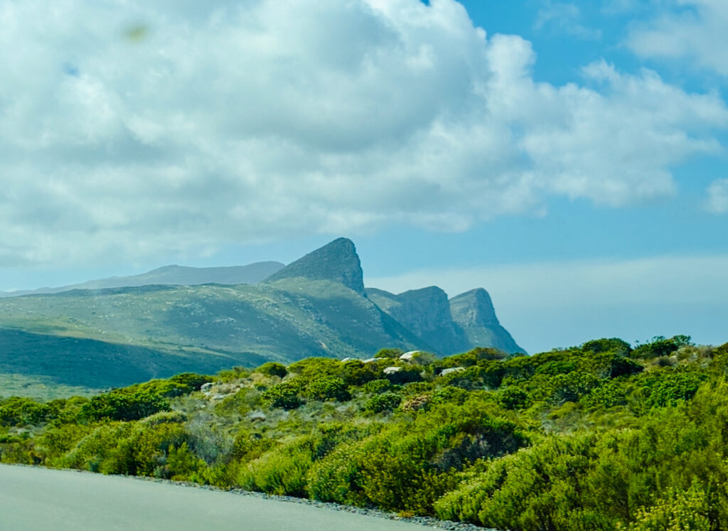Berglandschaft mit grünen Hängen unter blauem Himmel mit freundlichen Wolken