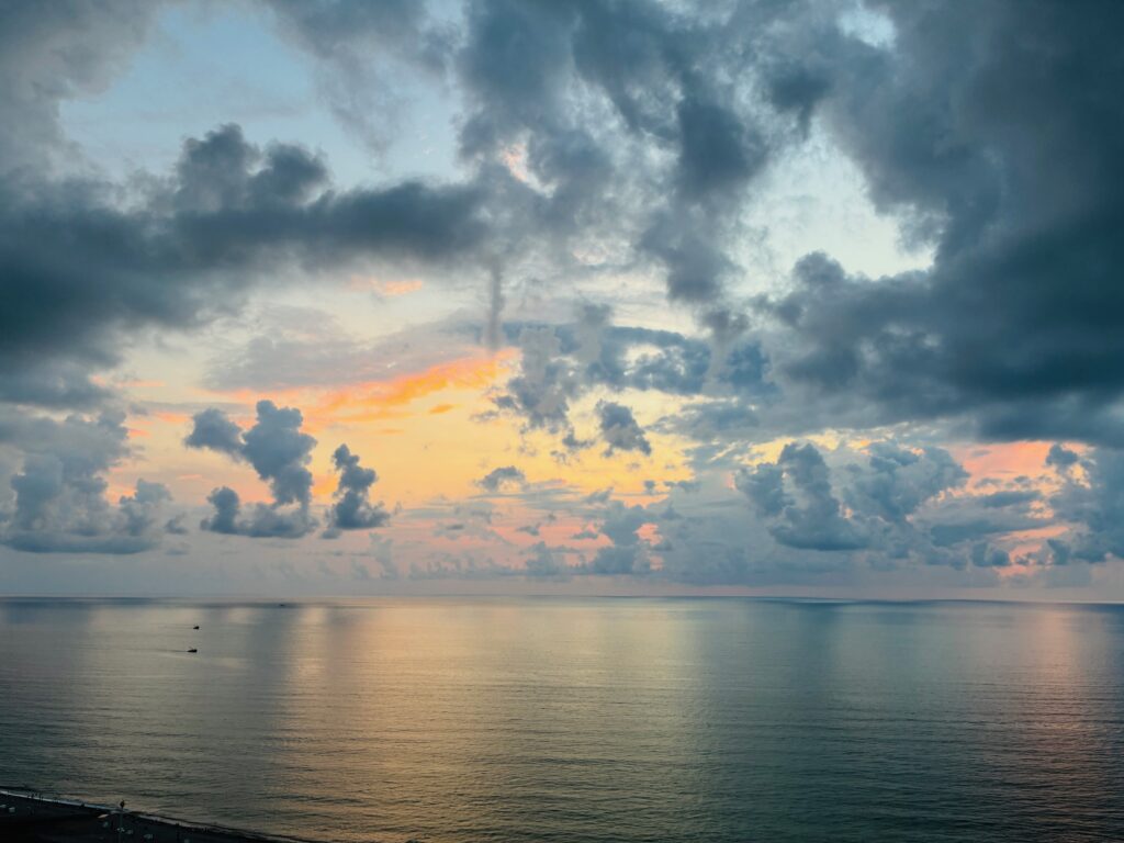 Dramatische Wolken bei Sonnenuntergang über glattem Meeresspiegel