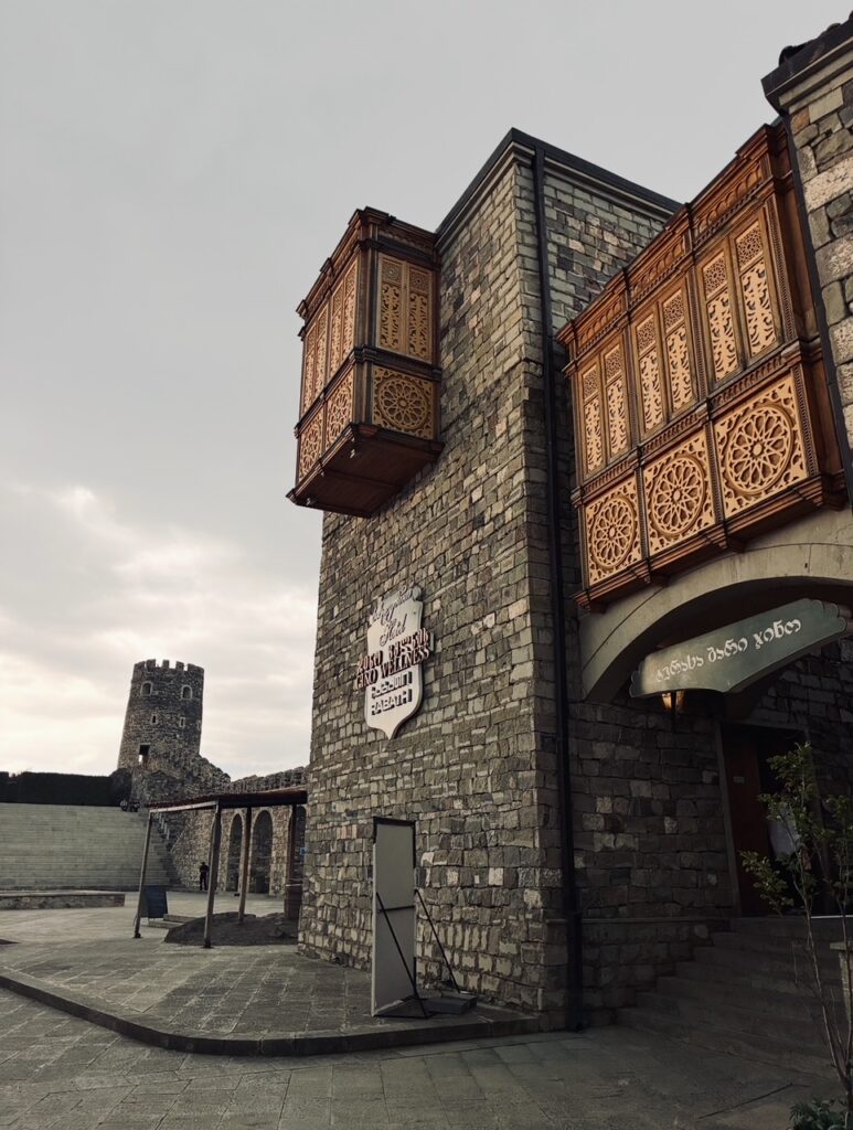 Steinerner Turm mit zwei kunstvoll verzierten hölzernen Erkern und einem runden Wehrturm im Hintergrund