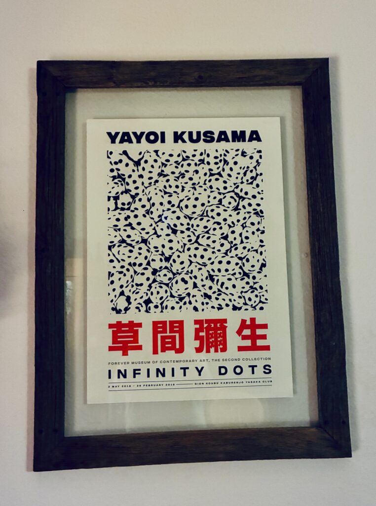 Gerahmtes Poster mit dem Titel 'Yayoi Kusama Infinity Dots' und einem Muster aus schwarzen Punkten auf weißem Hintergrund.