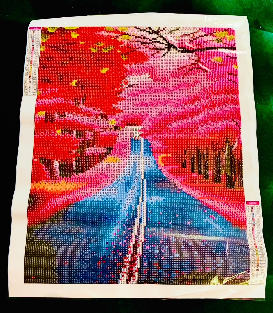 Unfertiges Diamond Painting-Bild mit einer Straße, die zwischen Bäumen mit roten und rosa Blättern in die Unendlichkeit führt