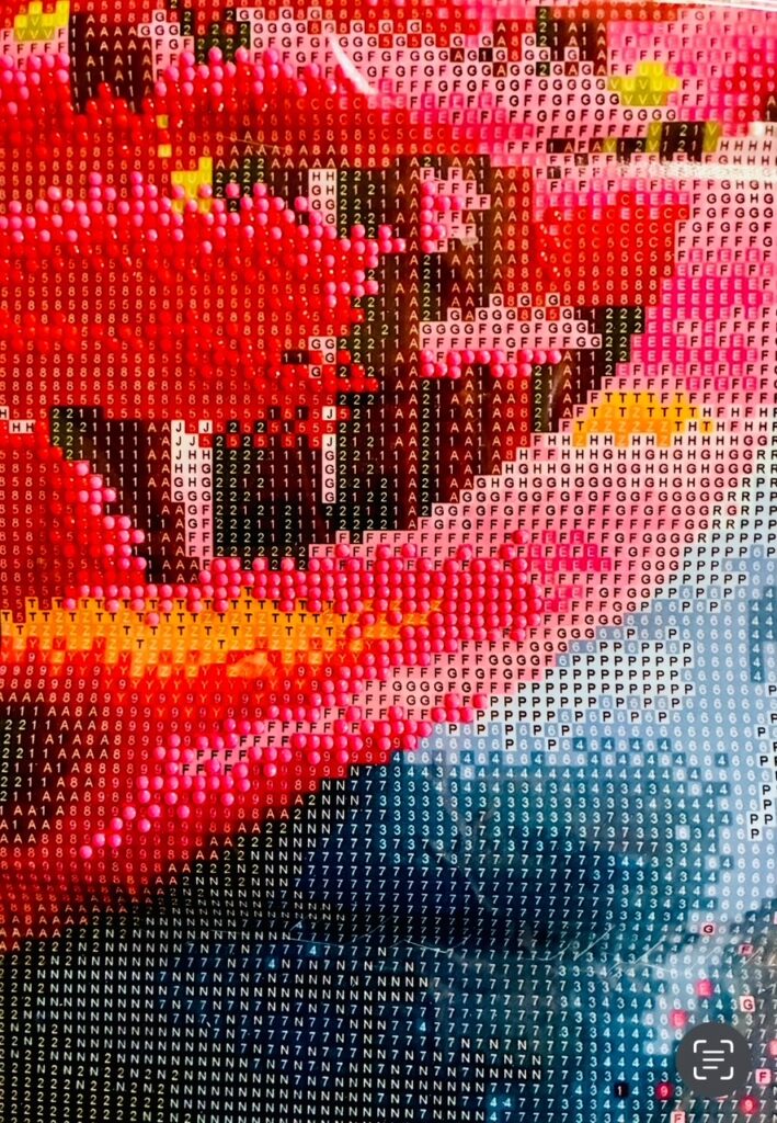 Nahaufnahme eines Mosaiks aus farbigen Quadraten mit Buchstaben und Zahlen. Es handelt sich um eine unfertige Diamond Painting-Arbeit